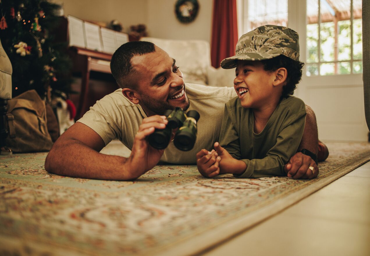 GettyImages-1408874734 A man and boy laying on the floor.