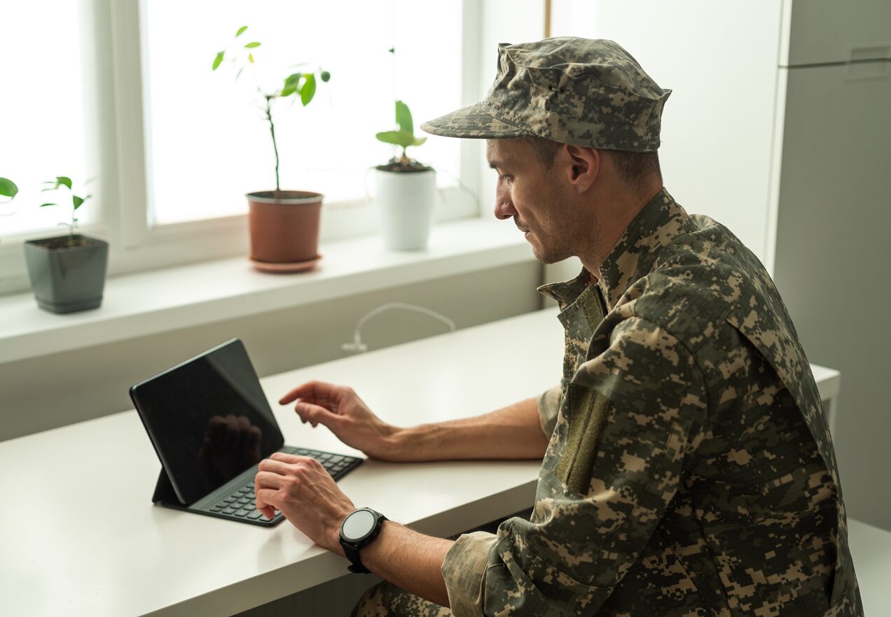 GettyImages-1941855870 A man in military uniform using his laptop.