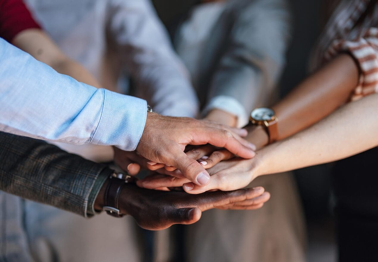 A group of people holding hands on top of a table.
