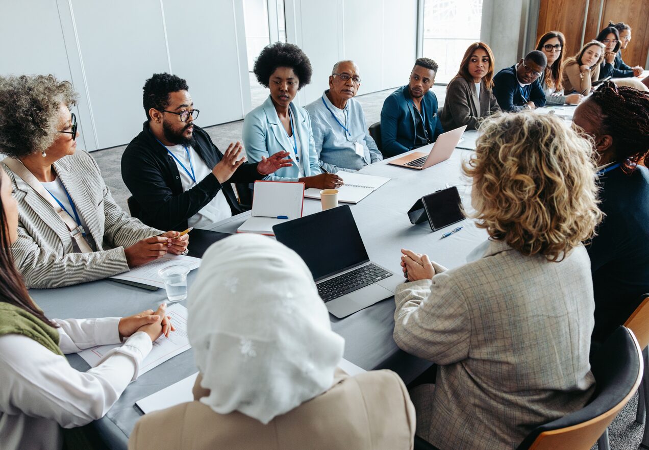 GettyImages-2189621574 A group of people sitting around a table.