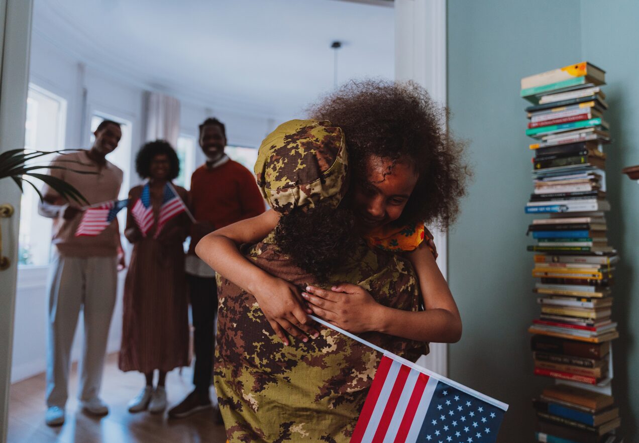 GettyImages-2191031890 A woman hugging another woman holding an american flag.