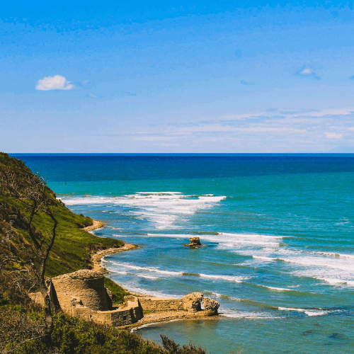 Coastal landscape with ruins and ocean waves.
