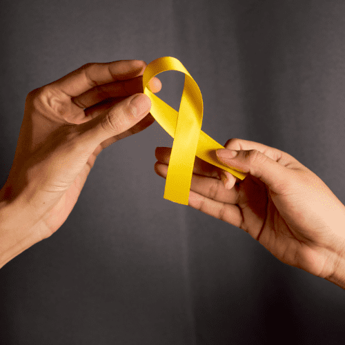 Hands holding a yellow awareness ribbon.
