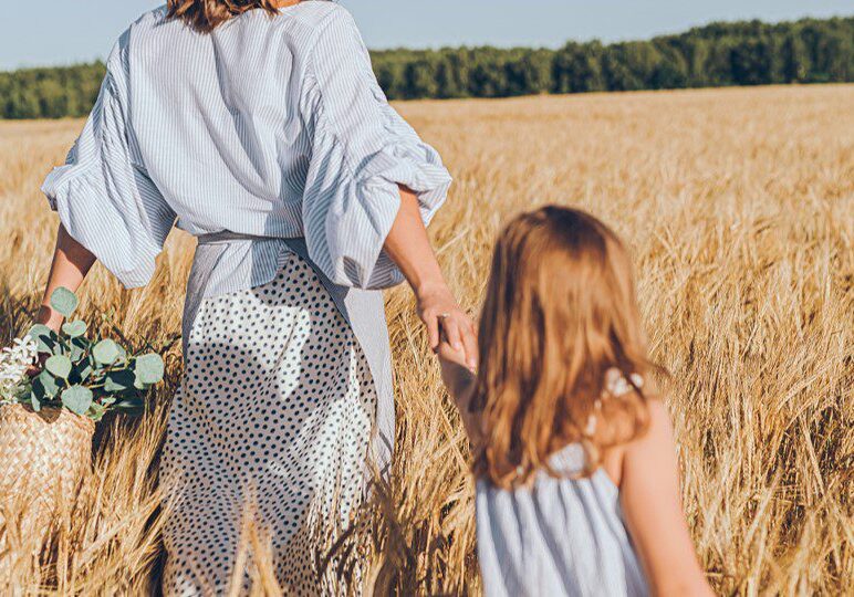 Mother and daughter walking through wheat field.