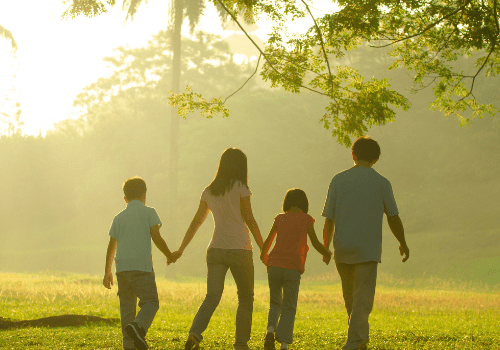 Family walking together in a sunny park.
